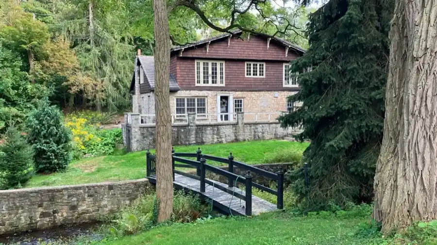 Historic Ancaster Mill stone building and footbridge among mature trees