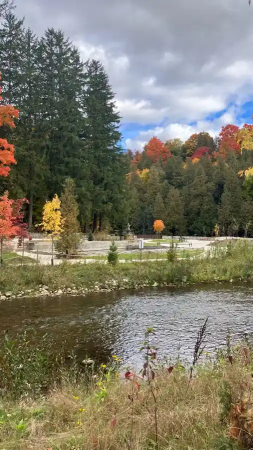Belfountain river channel with historic fountain terrace and fall trees beyond