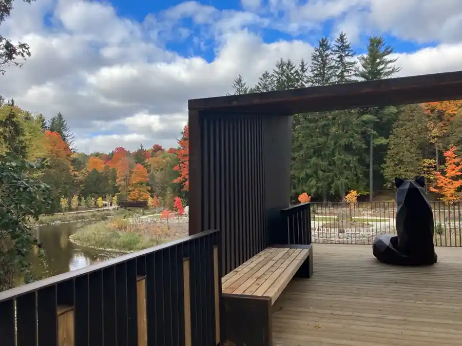 Black geometric Fox Folly sculpture at a Belfountain overlook above the river and fall trees