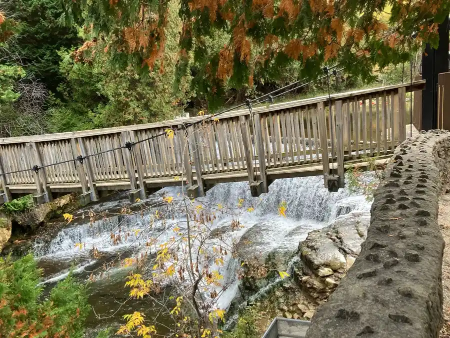 Wooden suspension bridge crossing above the Belfountain waterfall and rocky river