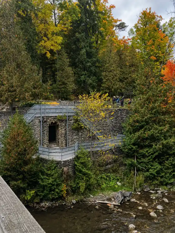Historic Yellowstone Cave replica with stone walls and metal stairs in Belfountain forest