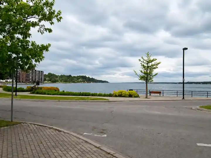 Brockville waterfront path, river bench and St Lawrence River under cloud cover