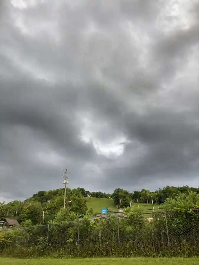 Green Glen Eden ski hill below dark summer storm clouds near Milton Ontario