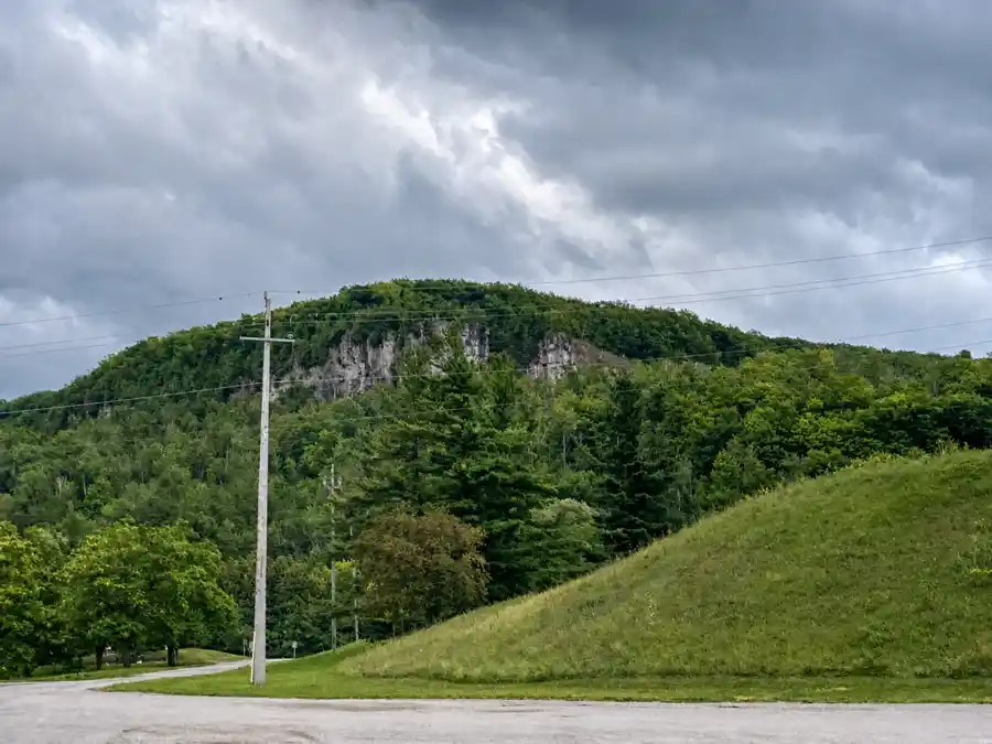 Exposed Niagara Escarpment rock and green forest rising beside Kelso Conservation Area
