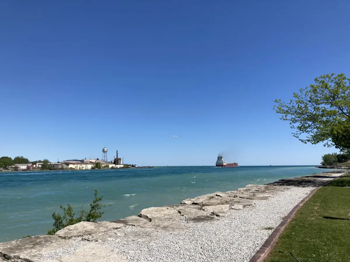 Navio e Port Huron à beira-mar através da água azul de Point Edward