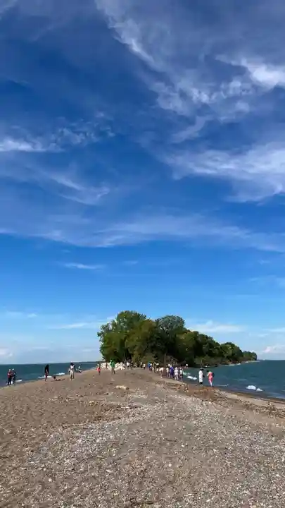 Visitors walking at the Point Pelee Tip toward the wooded peninsula and Lake Erie