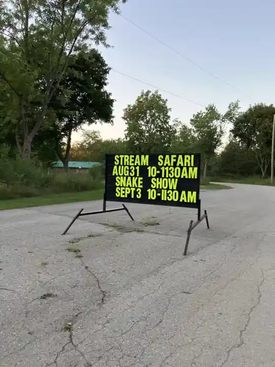 Past Wildwood Conservation Area sign advertising a stream safari and snake show