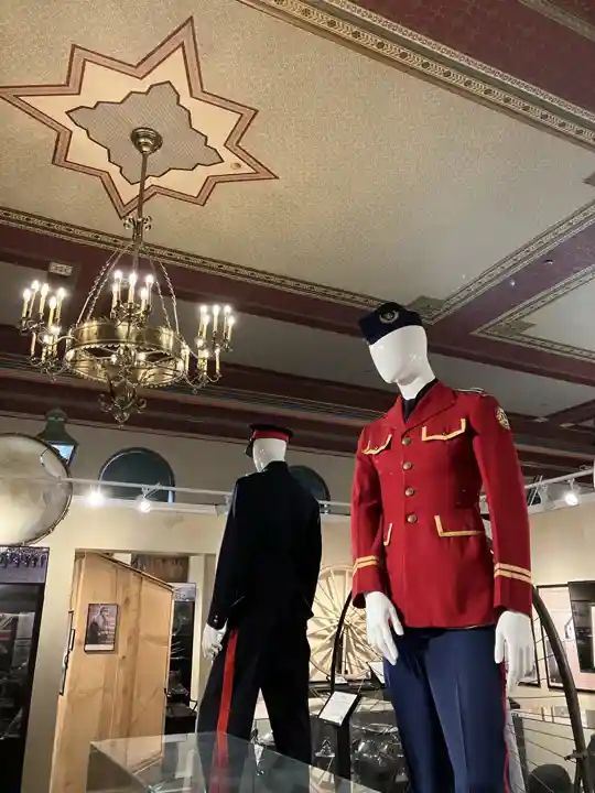 Historic red and dark uniforms displayed beneath the decorated ceiling of Woodstock Museum
